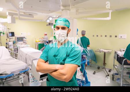 Chirurg mit Maske stehend mit Krankenschwester im Hintergrund im Krankenhaus Stockfoto