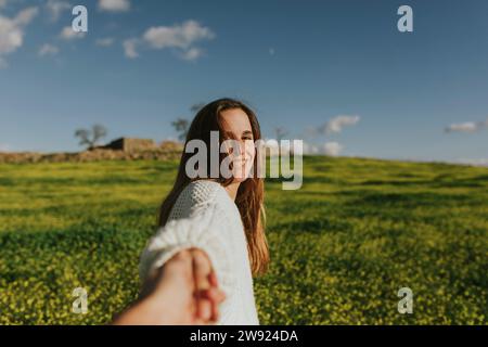 Glückliche Frau, die Hand eines Freundes auf der Wiese hält Stockfoto