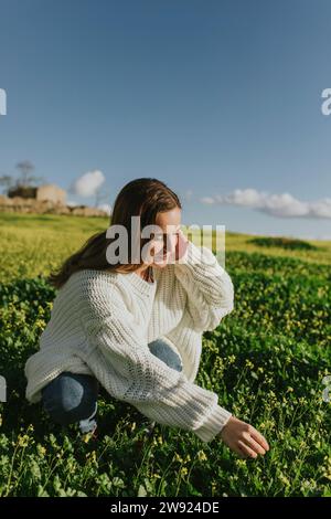 Frau, die Wildblumen an sonnigem Tag berührt Stockfoto