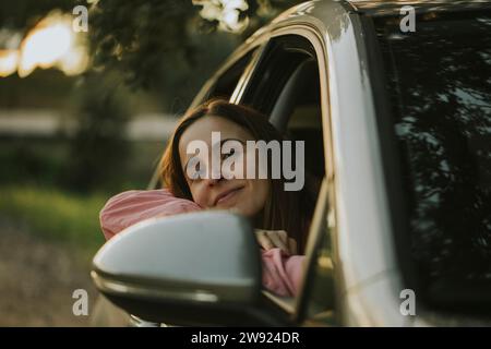 Nachdenkliche Frau, die sich auf das Autofenster lehnt Stockfoto