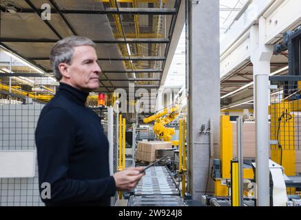 Manager, der Maschinen mit Tablet-PC im Werk bedient Stockfoto