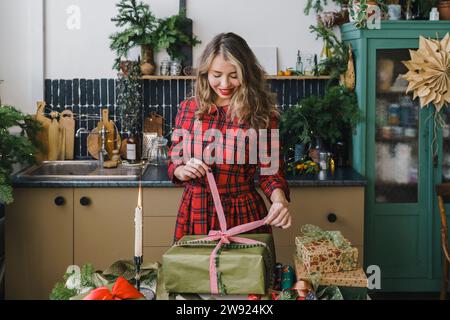 Lächelnde Frau, die zu Hause Weihnachtsgeschenke öffnet Stockfoto