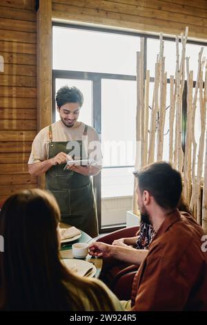 Kellner, der mit einem Tablet-PC Bestellungen von Gästen im Restaurant entgegennimmt Stockfoto