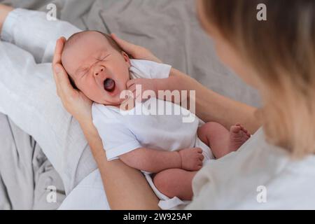 Neugeborener Junge, der auf dem Schoß der Mutter schläft und gähnt Stockfoto