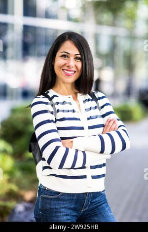Glückliche Frau, die mit verschränkten Armen steht Stockfoto