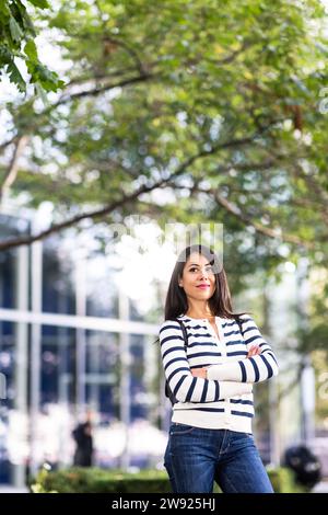 Nachdenklich stehende Frau mit verschränkten Armen Stockfoto