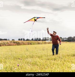 Ein verspielter Senior-Mann, der Drachen im Feld fliegt Stockfoto