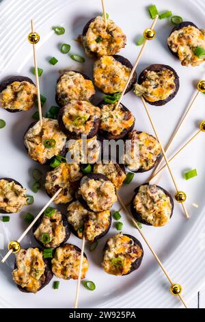 Eine Platte mit cremigem Käse gefüllten Pilzmützen, bereit zum Teilen. Stockfoto