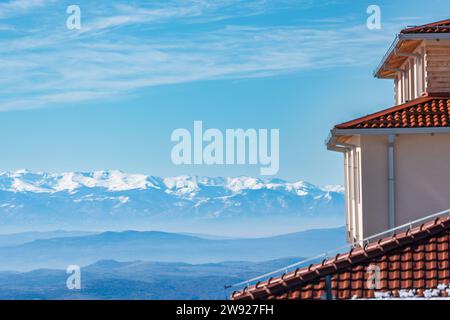 Gebäudearchitektur, Dachteil der Wohnung. Und Berggipfel mit Schnee bedeckt. Herrliche aussicht. Winterlandschaft. Stockfoto