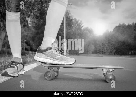 Bilder eines Beins, das auf einem Skateboard steht. Sonniger Abend im Park. Skateboarding-Konzept. Gemischte Medien Stockfoto