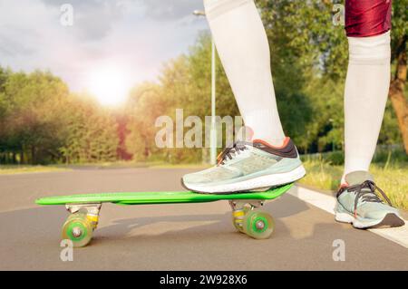 Bilder eines Beins, das auf einem Skateboard steht. Sonniger Abend im Park. Skateboarding-Konzept. Gemischte Medien Stockfoto