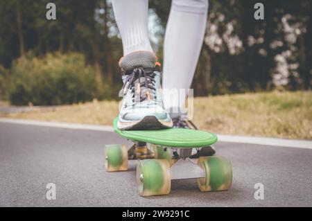 Bilder eines Beins, das auf einem Skateboard steht. Sonniger Abend im Park. Skateboarding-Konzept. Gemischte Medien Stockfoto