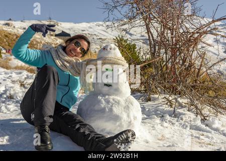 Schneekapaden Happy Latina Woman macht Erinnerungen mit Snowman Stockfoto