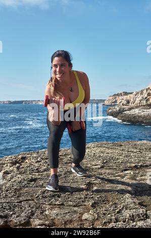 Lateinfrau mittleren Alters, Sportbekleidung trägt, trainiert, körperliche Übungen macht, Plank, Sit-ups, Kletterer Schritt, Kalorien verbrennen, fit halten Stockfoto