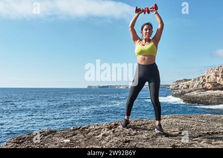 Lateinfrau mittleren Alters, Sportbekleidung trägt, trainiert, körperliche Übungen macht, Plank, Sit-ups, Kletterer Schritt, Kalorien verbrennen, fit halten Stockfoto