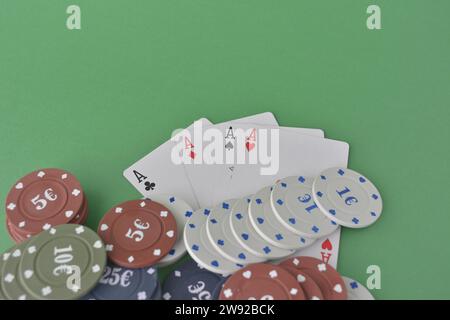 Eine Hand Asse über ordentlich gestapelten Pokerchips auf grünem Filz, was auf ein Gewinnspiel, Pokerkarten und Chips hindeutet Stockfoto