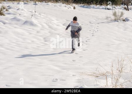Junger Mann, der Spaß hat, in großem Schnee zu laufen Stockfoto