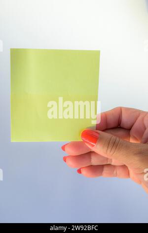 Frauenhand mit bemalten Nägeln, die leeres Briefpapier auf reinweißem Hintergrund halten Stockfoto