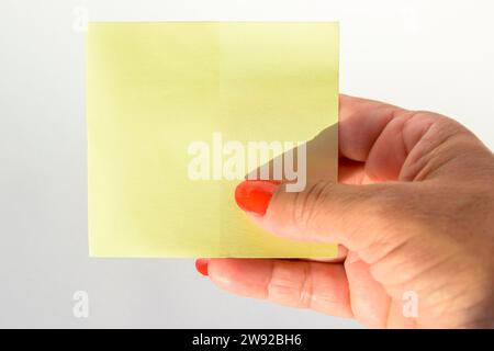 Frauenhand mit bemalten Nägeln, die leeres Briefpapier auf reinweißem Hintergrund halten Stockfoto