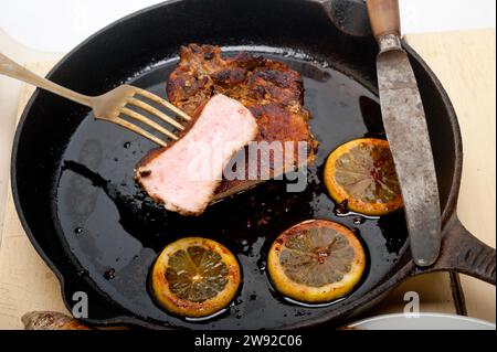 Schweinekoteletts auf einer Eisenpfanne mit Zitronen- und Gewürzwürzen, Lebensmittelfotografie, Lebensmittelfotografie Stockfoto