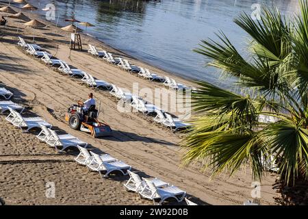 Am frühen Morgen am Sandstrand von Kusadasi. Die Liegen werden vorbereitet, der Sand wird gepflegt, Kusadasi, Kusadasi, Provinz Aydin, Ägäis Stockfoto