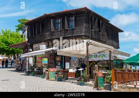 Altes Holzhaus mit Straßencafé im Vordergrund unter sonnigem, bewölktem Himmel, Altstadt, typische Schwarzmeerarchitektur, Sosopol, Sozopol Stockfoto