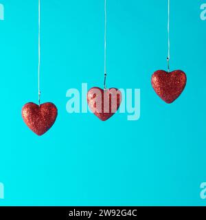 Drei rote Herzen in Fischhaken auf blauem Hintergrund. Love-Konzept Stockfoto
