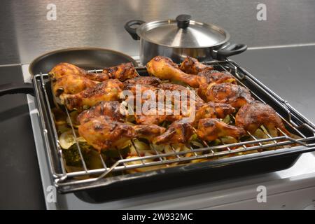 Hühnerstücke auf einem Metallgitter mit einem Backblech Gemüse wie Kartoffeln, Zucchini, Paprika, Zwiebeln, Brokkoli Stockfoto