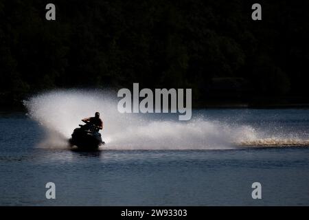 Silhouette eines Mannes auf einem Jetski auf einem See im Sommer, horizontal Stockfoto