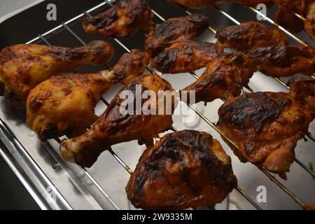 Köstliches Essen, gebackene Hühnerstücke in Form von Beinen und Flügeln von gegrillten Hühnern, mariniert mit einer köstlichen roten Würze. Stockfoto