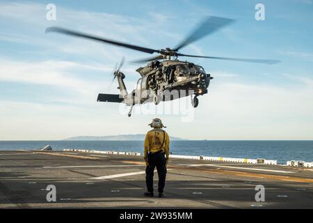 PAZIFIK (10. Dezember 2023) - Ein MH-60M Black Hawk der US-Armee, der dem 4. Bataillon, 160. Special Operations Aviation Regiment (Airborne), mit eingestiegenen Naval Special Warfare (NSW)-Operatoren, angehört, landet während der gemeinsamen Landungsqualifikation an Bord des amphibischen Angriffsschiffs USS Boxer (LHD 4) im PAZIFIK, 10. Dezember, 2023. Die Marine Special Warfare ist die Elite-Spezialeinsatztruppe des Landes, die einzigartig positioniert ist, um die Reichweite der Flotte zu erweitern und Dynamik und Zugang für die Joint Force in Wettbewerb und Konflikt zu gewinnen. Die 15. Marine Expeditionary Unit ist derzeit an Bord Stockfoto