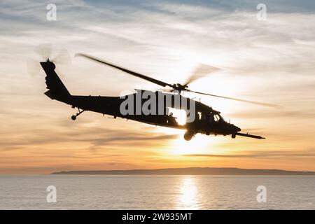 PAZIFIK (10. Dezember 2023) - Ein MH-60M Black Hawk der US-Armee, der dem 4. Bataillon, 160. Special Operations Aviation Regiment (Airborne), mit eingestiegenen Naval Special Warfare (NSW)-Operatoren über den Pazifik fliegt, während sie gemeinsame Landungsqualifikationen an Bord des amphibischen Angriffsschiffs USS Boxer (LHD 4) durchführen. Dezember 2023. Die Marine Special Warfare ist die Elite-Spezialeinsatztruppe des Landes, die einzigartig positioniert ist, um die Reichweite der Flotte zu erweitern und Dynamik und Zugang für die Joint Force in Wettbewerb und Konflikt zu gewinnen. Die 15. Marine Expeditionary Unit ist derzeit EM Stockfoto