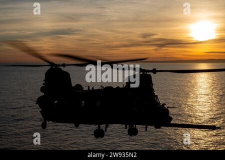 PAZIFIK (10. Dezember 2023) - Ein Chinook der US-Armee MH-47G, der dem 4. Bataillon, 160. Special Operations Aviation Regiment (Airborne), mit eingestiegenen Naval Special Warfare (NSW)-Operateuren über den Pazifik fliegt während der gemeinsamen Landungsqualifikation mit an Bord des amphibischen Angriffsschiffs USS Boxer (LHD 4), 10. Dezember, 2023. Die Marine Special Warfare ist die Elite-Spezialeinsatztruppe des Landes, die einzigartig positioniert ist, um die Reichweite der Flotte zu erweitern und Dynamik und Zugang für die Joint Force in Wettbewerb und Konflikt zu gewinnen. Die 15th Marine Expeditionary Unit ist derzeit an Bord einer Stockfoto