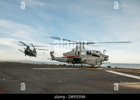 PAZIFIK (10. Dezember 2023) - Ein MH-47G Chinook der US-Armee, links, angefügt am 4. Bataillon, 160. Special Operations Aviation Regiment (Airborne), mit eingestiegenen Naval Special Warfare (NSW) Operatoren landet hinter einem Marinekorps AH-1Z Viper, das der mittleren Tiltrotor Squadron (VMM) 165 (verstärkt), 15. Marine Expeditionary Unit, während der gemeinsamen Landungsqualifikation an Bord des amphibischen Angriffsschiffs USS Boxer (LHD 4) im Pazifischen Ozean am 10. Dezember 2023. Die Marine Special Warfare ist die Elite-Spezialeinsatztruppe des Landes, die einzigartig positioniert ist, um die Reichweite A der Flotte zu erweitern Stockfoto