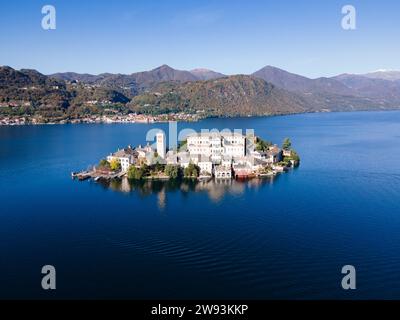 San Giulio Island im Orta-See im Piemont, Italien. Drohnenansicht aus der Luft im Herbst. Berge, blaues Wasser und Reflexion Stockfoto