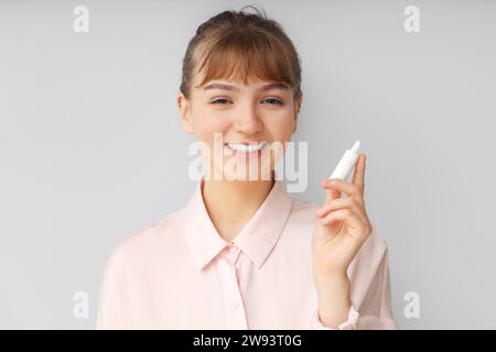 Junge Geschäftsfrau mit Augentropfen auf hellem Hintergrund, Nahaufnahme. Glaukombewußtsein Monat Stockfoto