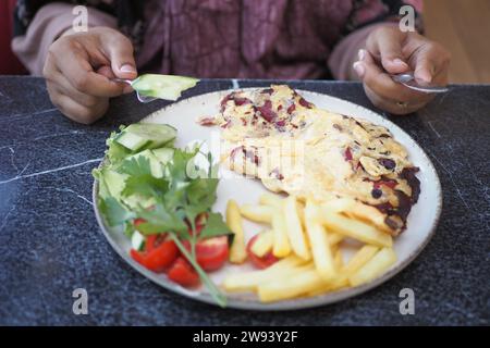 Frauen essen gemischtes Fleisch Ei Omelette serviert mit Salat Stockfoto