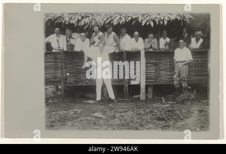 Gruppenporträt der Mitarbeiter in Moengo., 1929 - 1930 Postkarte eines Fotos. Eine Reihe Leute hinter einem Zaun. Zwei Männer sind vorne. Rechts posiert eine kreolische Frau. Rückseite der Schreibzeilen. Suriname-Papier druckt Moengo. Albina Stockfoto