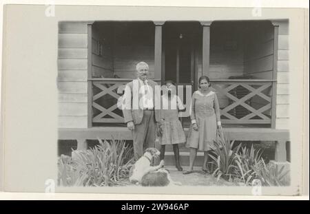 Gruppenfoto in Moengo, 1929 - 1930 Postkarte eines Fotos von Einem Mann, zwei Frauen und zwei Hunden für ein Haus. Rückseite der Schreibzeilen. Suriname-Papier druckt Moengo. Albina Stockfoto