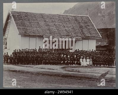 Gruppenfoto von Soldaten, 1903 - 1913 Foto, das eine große Gruppe von Soldaten der KNIL vor einem Haus darstellt. In der ersten Reihe einige höhere Offiziere mit weißen Federn auf dem Helm und vier Frauen. Die gleiche Gruppe wie auf den Fotos der eidesstattlichen Zeremonie. Gepacktes Foto in einem Album mit 87 Fotos über den Bau des Gajoweges auf Noord-Sumatra zwischen Bireuen und Takinguen zwischen 1903 und 1914. Noord-sumatra fotografische Unterstützung Gajoweg Stockfoto