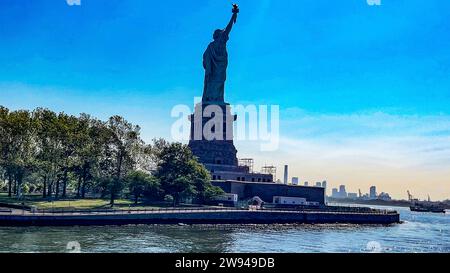 Die Dame von New York (USA) von hinten gesehen und ein Boot, so ist die Freiheitsstatue des Big Apple bekannt, besucht und weltweit bekannt. Stockfoto