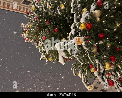 München, Deutschland. Dezember 2023. Dicke Schneeflocken fallen vom Himmel über einem geschmückten Weihnachtsbaum im Zentrum Münchens. Quelle: Matthias Balk/dpa/Alamy Live News Stockfoto