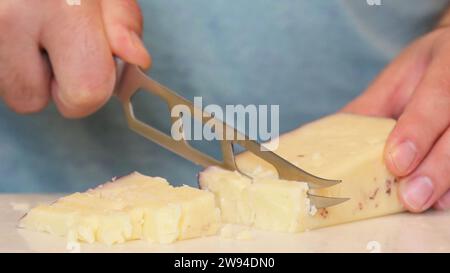 Käseblock-ganzer Käseblock verwandelt sich mit Finesse, während ein erfahrener Koch ein Käseschneidemesser führt. Jeder präzise Schnitt enthüllt kulinarische Kunst. Stockfoto