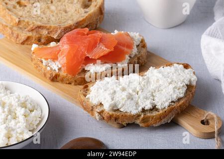 Sandwich mit gesalzenem Lachs und Hüttenkäse auf einem Holztisch Stockfoto