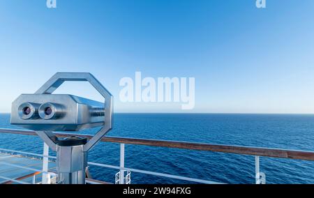 Ferngläser auf dem Deck eines Kreuzfahrtschiffs auf See mit wolkenlosem blauem Himmel. Stockfoto