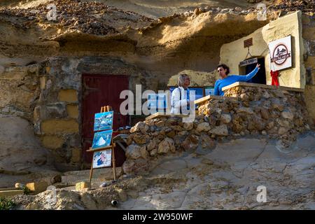 Josephine Xuereb am Eingang zum kleinen Verkaufsraum über den Salinen in Gozo, Xwejni Bay. Leli Tal-Melh Salzladen in Xwejni in der Nähe von Marsalforn, Gozo, Malta Stockfoto