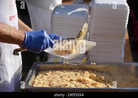 Pula, Kroatien. Dezember 2023. Personen, die einen Teil eines traditionellen Risottos mit Meeresfrüchten (Risotto ai Fruitti di Mare) während eines traditionellen Weihnachtsessens am Weihnachtsabend auf dem Stadtmarkt in Pula, Kroatien, erhalten am 24. Dezember 2023. Foto: SASA Miljevic/PIXSELL Credit: Pixsell/Alamy Live News Stockfoto