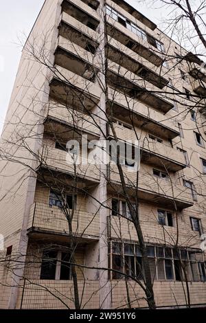 Bäume im Vordergrund verdecken teilweise ein großes, mehrstöckiges Gebäude. Stockfoto