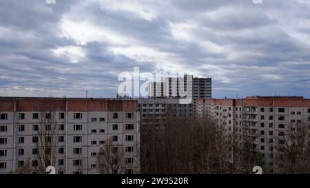 Das Bild zeigt alte Wohnungen mit einem dramatischen bewölkten Himmel und blattlosen Bäumen. Stockfoto