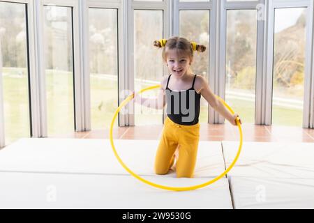 Kleines blondes Mädchen mit schwanzigen Schwänzen, das mit Hula Hoop spielt Stockfoto